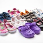 A pair of comfortable toddler travel shoes sitting on a sunny wooden boardwalk.