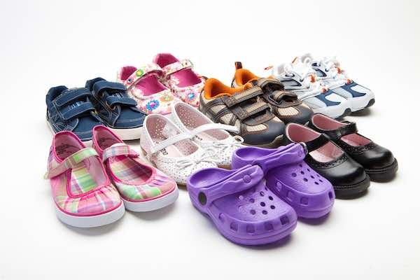 A pair of comfortable toddler travel shoes sitting on a sunny wooden boardwalk.