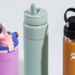 A variety of colorful, durable kids' travel water bottles sitting on a wooden table.
