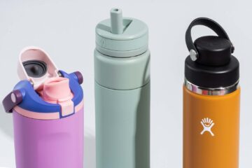 A variety of colorful, durable kids' travel water bottles sitting on a wooden table.
