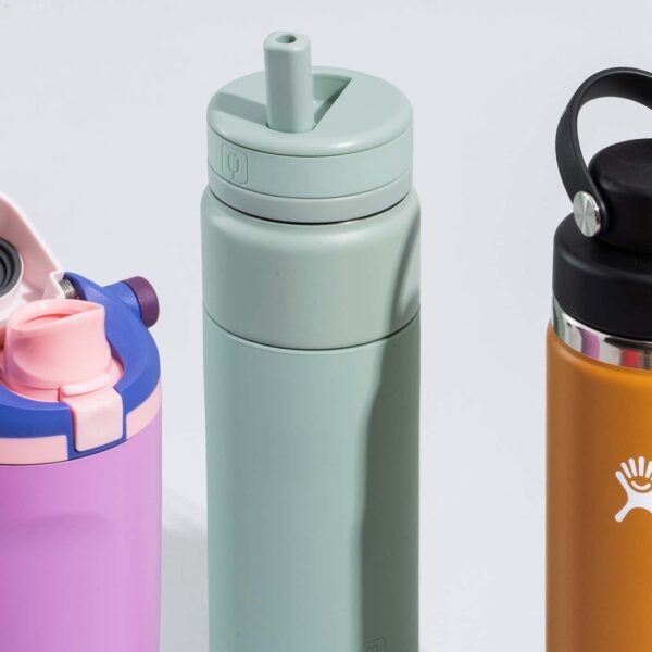 A variety of colorful, durable kids' travel water bottles sitting on a wooden table.