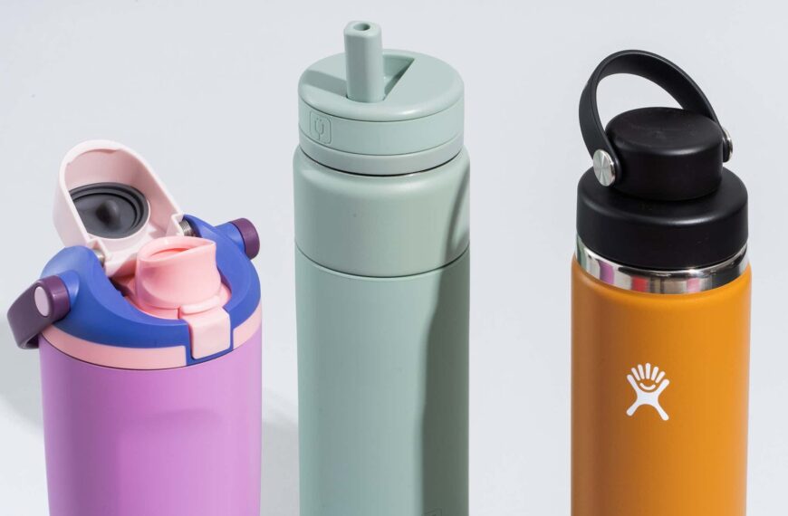 A variety of colorful, durable kids' travel water bottles sitting on a wooden table.