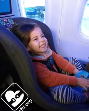 Hands installing the Cosco Scenera Next rear-facing with an airplane seat belt