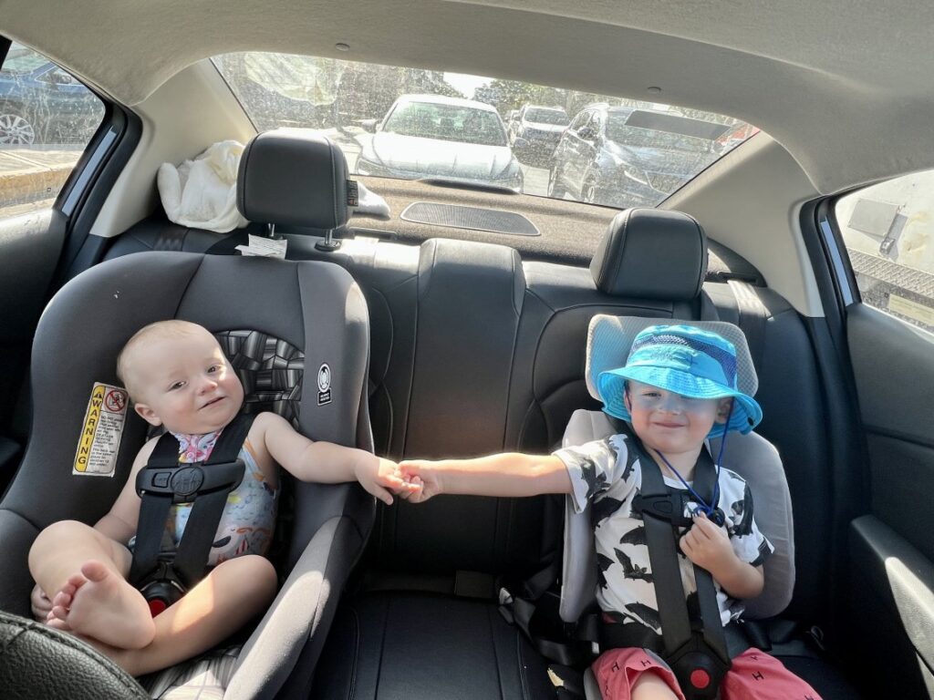 Two travel car seats compared side by side on a wooden bench