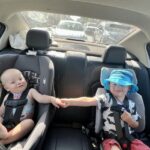 Two travel car seats compared side by side on a wooden bench