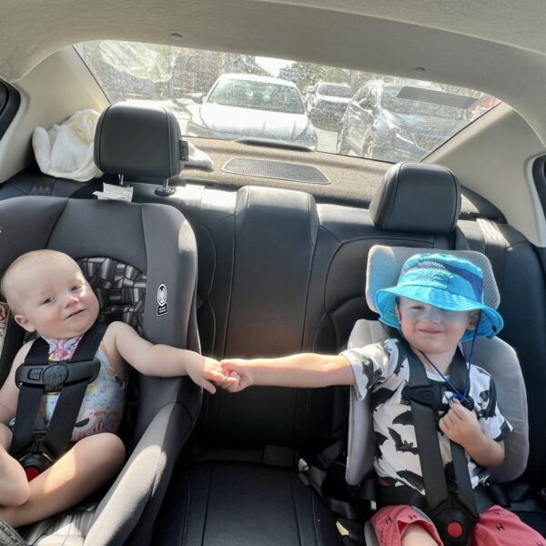 Two travel car seats compared side by side on a wooden bench