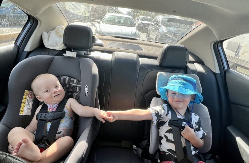 Two travel car seats compared side by side on a wooden bench