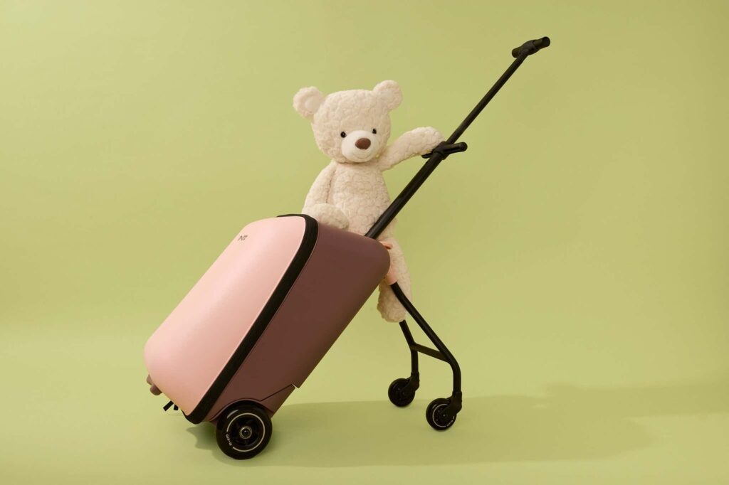 A young toddler pulling a carry-on suitcase through a bright, modern airport terminal.
