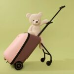 A young toddler pulling a carry-on suitcase through a bright, modern airport terminal.
