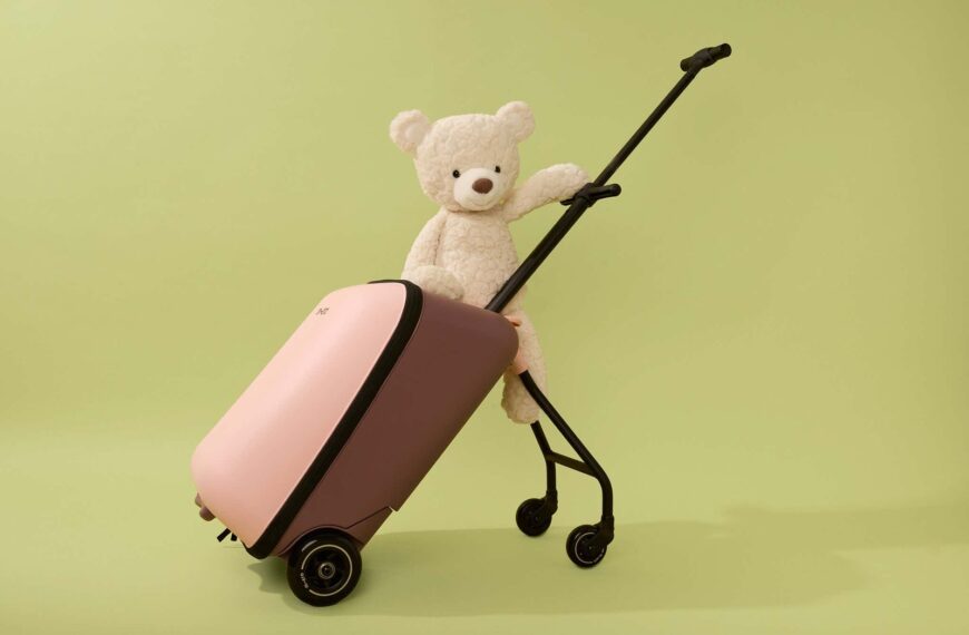 A young toddler pulling a carry-on suitcase through a bright, modern airport terminal.
